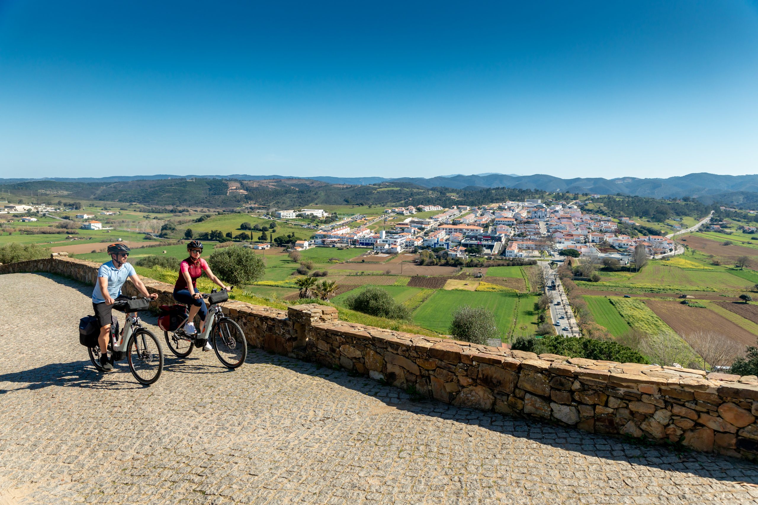 Two riders on gravel path by the ocean