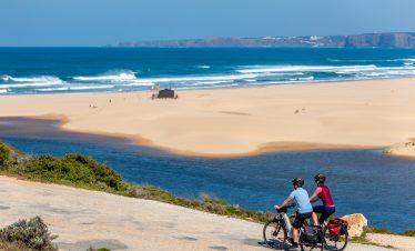 Cyclists pedaling near Atlantic beach in Portugal