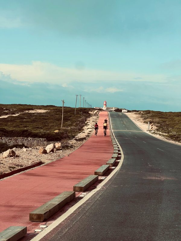 Cyclists riding towards Cabo de São Vicente lighthouse