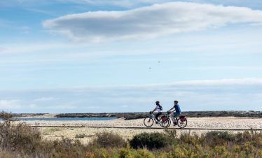 Cyclists riding along the EuroVelo 1 route at Ria Formosa Natural Park Algarve Portugal